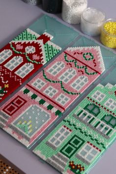 two cross stitch coasters sitting on top of a table next to candles and candy