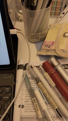 an open laptop computer sitting on top of a desk next to pens and pencils