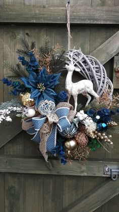 a christmas wreath hanging from the side of a wooden door with deer and pine cones