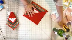 a woman is making christmas decorations with red and green material on the table next to her