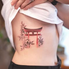 a woman with a tattoo on her back holding onto the side of her stomach,