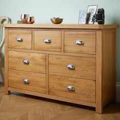 a wooden dresser with many drawers and silver knobs on it's sides, in a room