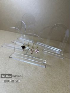 three pairs of earrings on display in a clear acrylic case with black and pink crystals