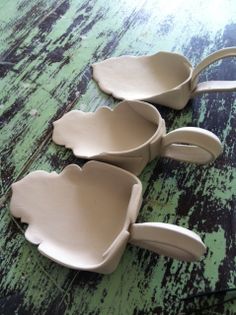 three ceramic flower shaped dishes sitting on top of a wooden table next to each other