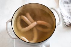 hot dog buns are being cooked in a pot on the stove top with water