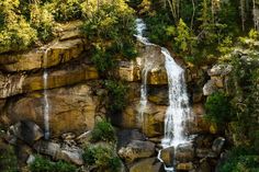 the waterfall is surrounded by trees and rocks