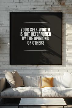 a living room with a white couch and black framed poster on the wall that says, your self - worth is not determined by the opinions of others