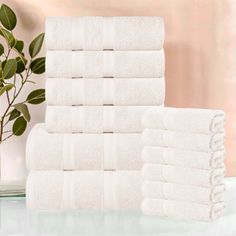 a stack of white towels sitting on top of a table next to a potted plant