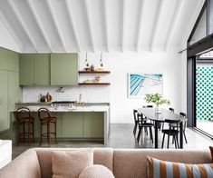 an open kitchen and living room area in a modern home with green cabinets, white walls, and wood floors