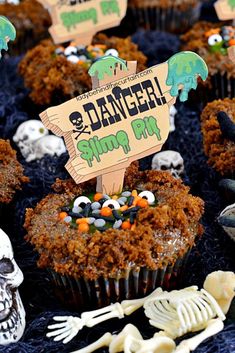 cupcakes decorated with halloween decorations and skeleton bones on a black tablecloth covered table