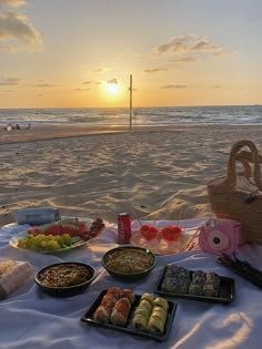 a picnic on the beach with food and drinks in front of the ocean at sunset