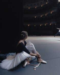 a woman sitting on the floor in front of a man who is holding a ballerina