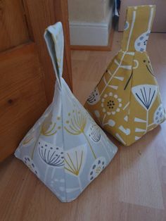 two small vases sitting on top of a wooden floor next to each other in front of a door