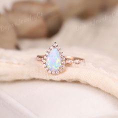 an opal and diamond ring sits on a white cloth