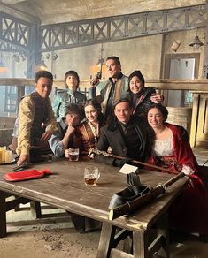 a group of people posing for a photo in front of a table with a beer