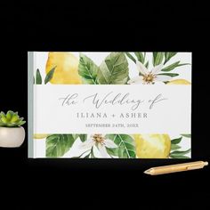 a wedding guest book with lemons, leaves and flowers on it next to a pen