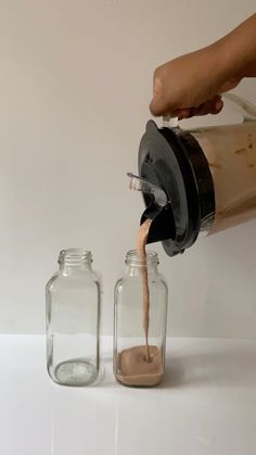 a person pours coffee into two glass jars