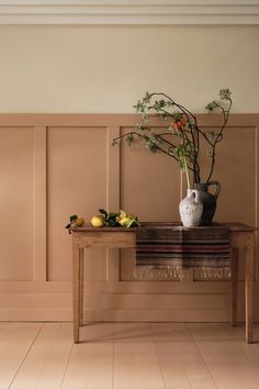 a table with a vase and some fruit on it