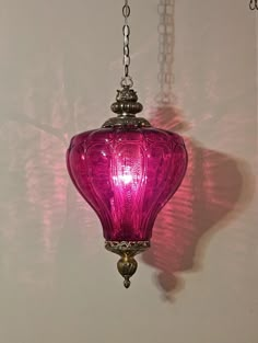 a pink glass light hanging from a chain