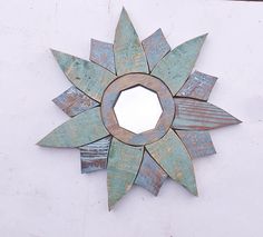 a decorative metal sunburst hanging on the side of a white wall with wood planks