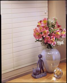 a vase filled with pink flowers sitting on top of a table next to a small figurine