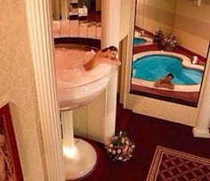 a woman in a bathtub inside of a bathroom next to a sink and mirror