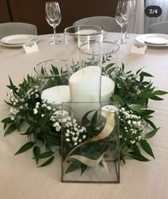 a centerpiece with candles and greenery on a table