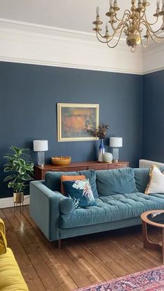 a living room filled with furniture and a chandelier hanging above the couches