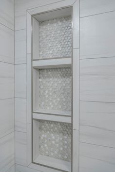 a white shelf with three shelves in the middle and one on the other side, next to a tiled wall