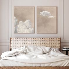 two paintings on the wall above a bed in a room with white sheets and pillows