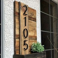 a wooden house number sign sitting on top of a window sill next to a potted plant