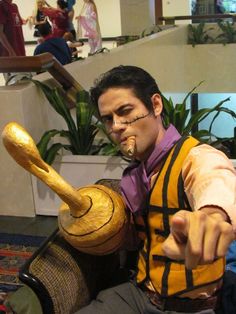 a man sitting on top of a chair holding a wooden object in his hand and pointing at it