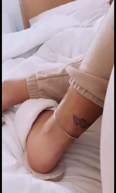 a woman's foot with a small tattoo on her left ankle, laying on a bed