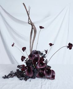 a vase filled with flowers on top of a white cloth covered table next to a branch