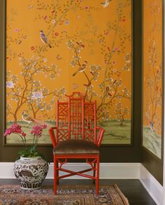 a chair sitting in front of a painting on the wall next to a potted plant