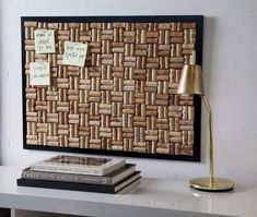 a white table topped with two books and a lamp next to a cork bulletin board