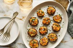 a white plate topped with crab cakes next to a glass of water and silverware