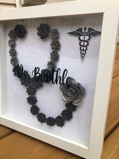 a shadow frame with some flowers and a stethoscope in the shape of a heart