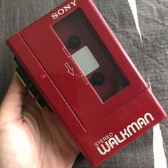 a hand holding a red sony cassette player