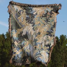 an old blanket hanging on a clothes line in front of some trees and blue sky