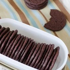 chocolate cookies in a white dish on a striped tablecloth next to two heart shaped cookies