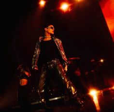 a man standing on top of a stage in front of a microphone and some lights