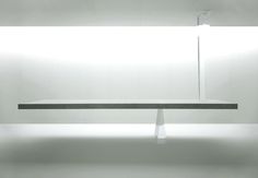 an empty bench in a white room with light coming through the window to reveal it