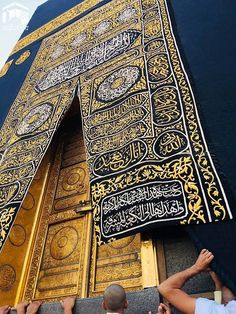 people are standing in front of a tall building with gold and black decorations on it