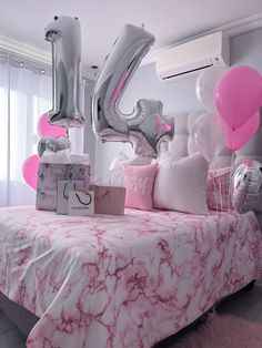 a bed with pink and silver decorations on it, including balloons in the shape of the number 50