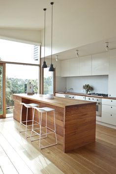 a kitchen with an island and bar stools in it's center room area