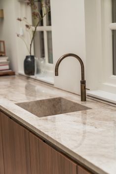 a kitchen sink sitting under a window next to a counter top with a faucet