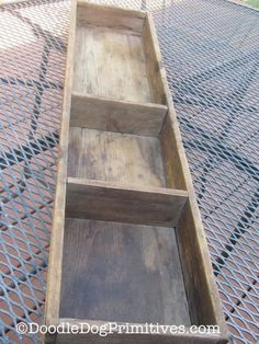 an empty wooden box sitting on top of a metal grating area with the lid open