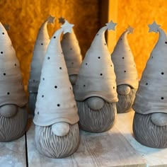 five ceramic gnomes with hats and stars on their heads are sitting on a table