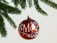 a red ornament hanging from a christmas tree with the word merry written on it